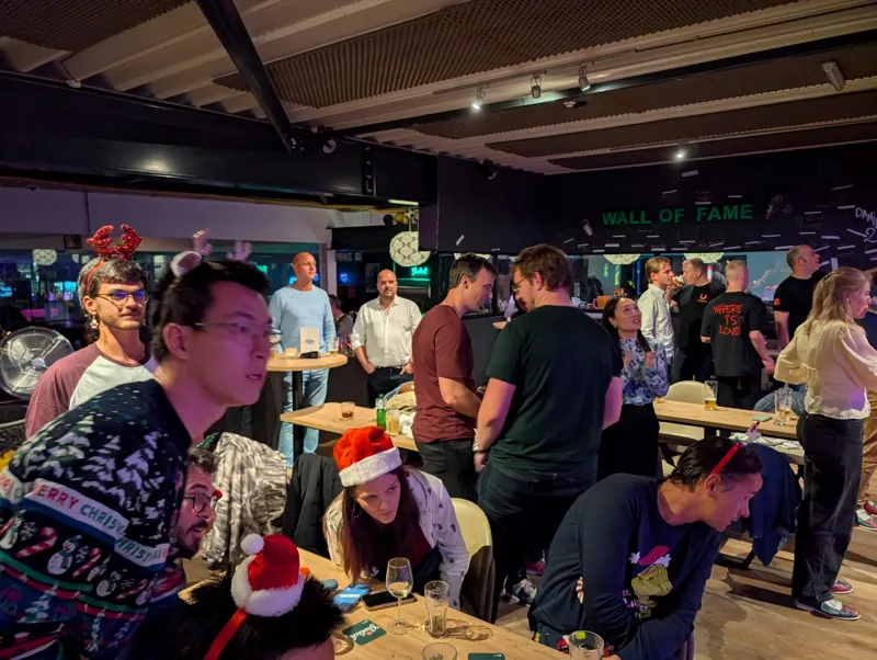 Volle zaal met kerstmutsen en de Wall of Fame op de achtergrond